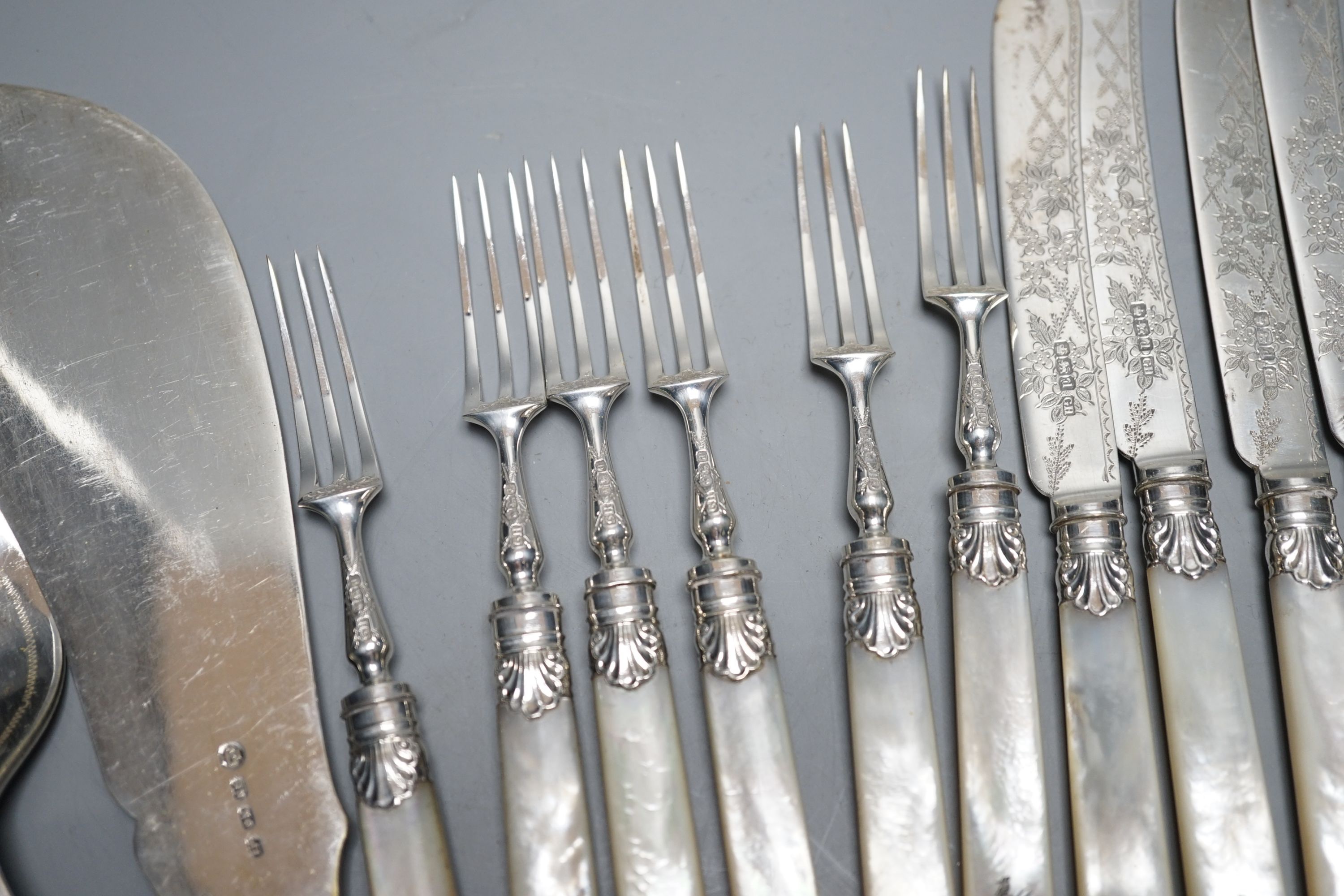 Six pairs of George V mother of pearl handled silver dessert eaters, George Howson, Sheffield, 1921, a pair of silver sugar tongs and assorted plated flatware.
